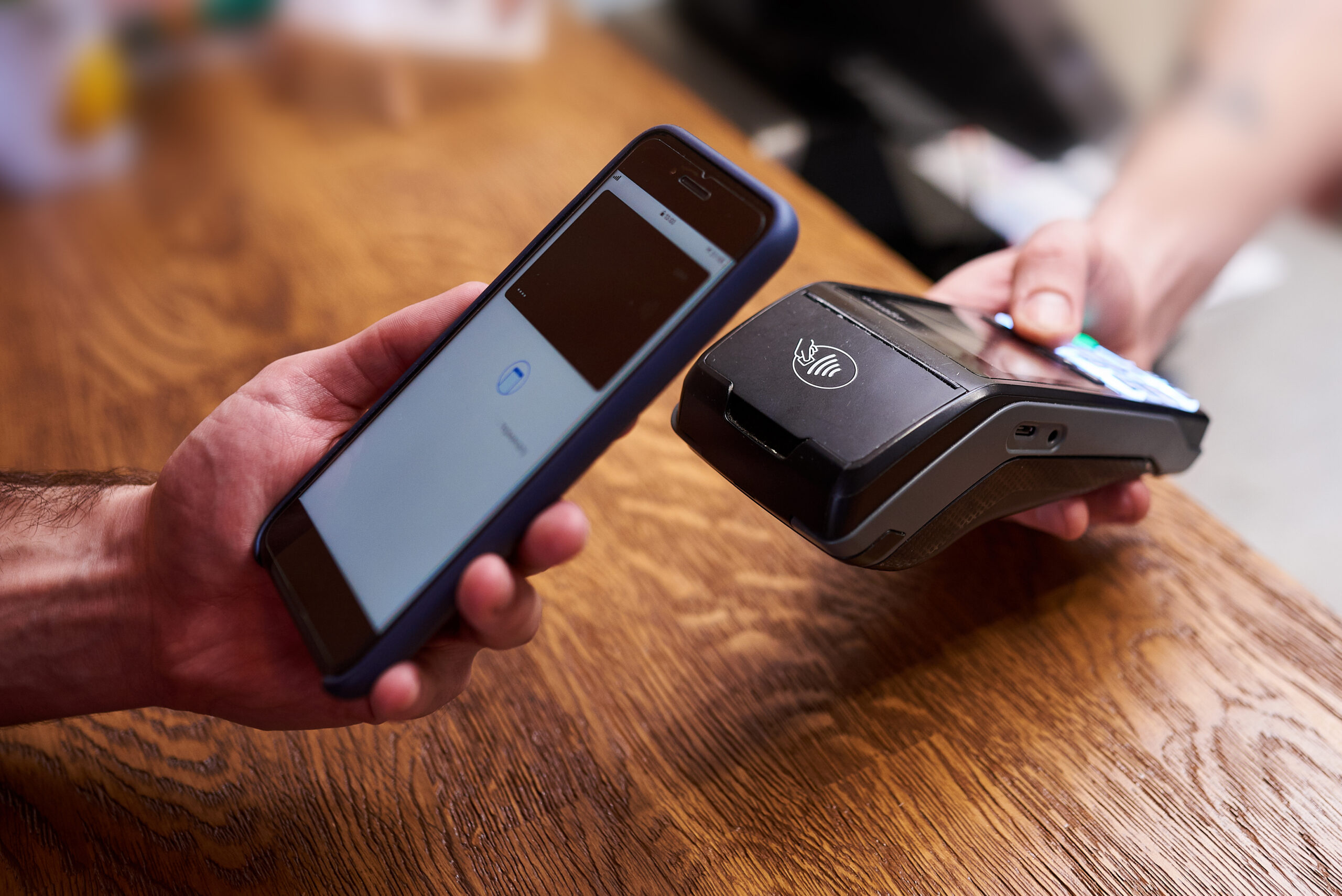 person holding a digital wallet to a card reader